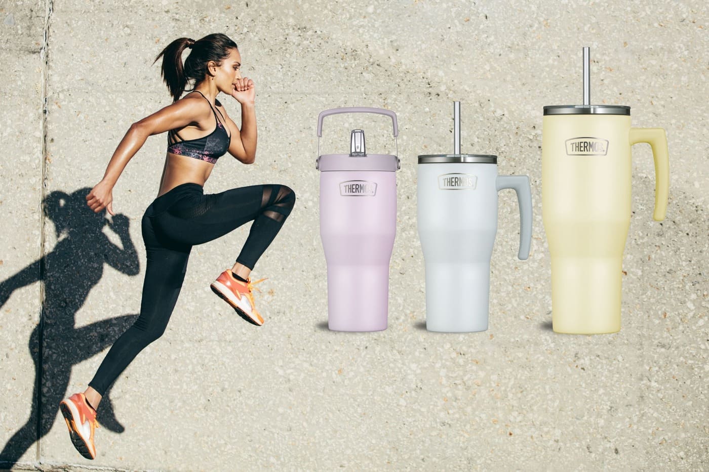 Eine sportlich gekleidete Frau springt vor einer Betonwand; daneben stehen drei große Refreshing Becher mit Strohhalm in Pastellfarben.