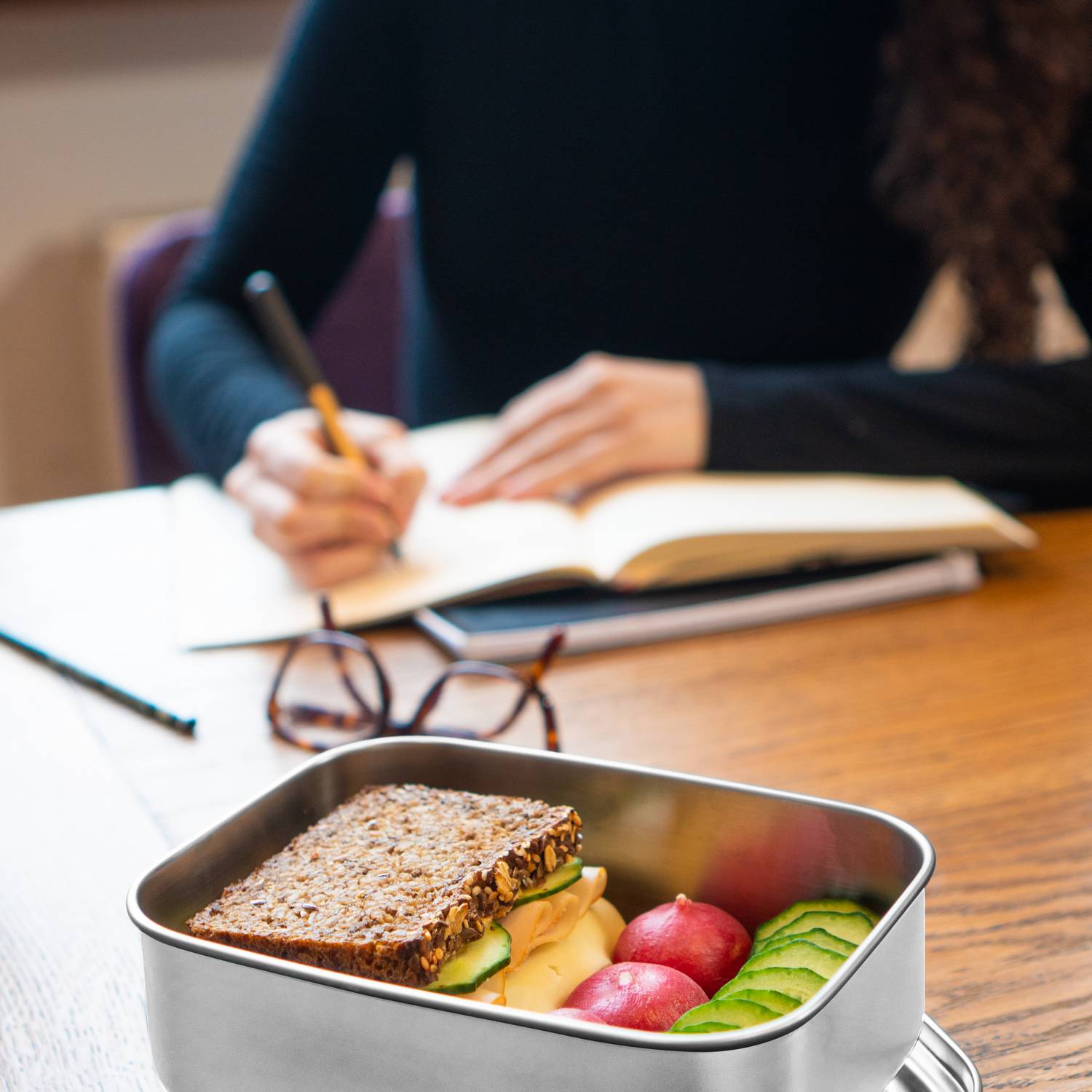Eine Person sitzt draußen und hält einen türkisfarbenen THERMOS ICON Kids Food Jar mit Löffel.