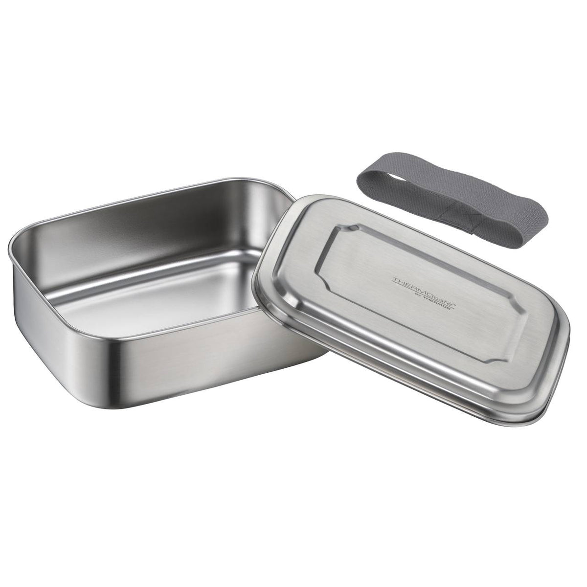 Es ist eine rechteckige Brotdose aus Metall, die geöffnet ist, sodass der Deckel daneben liegt. Neben der Dose befindet sich ein graues elastisches Band, vermutlich zur Sicherung des Deckels.