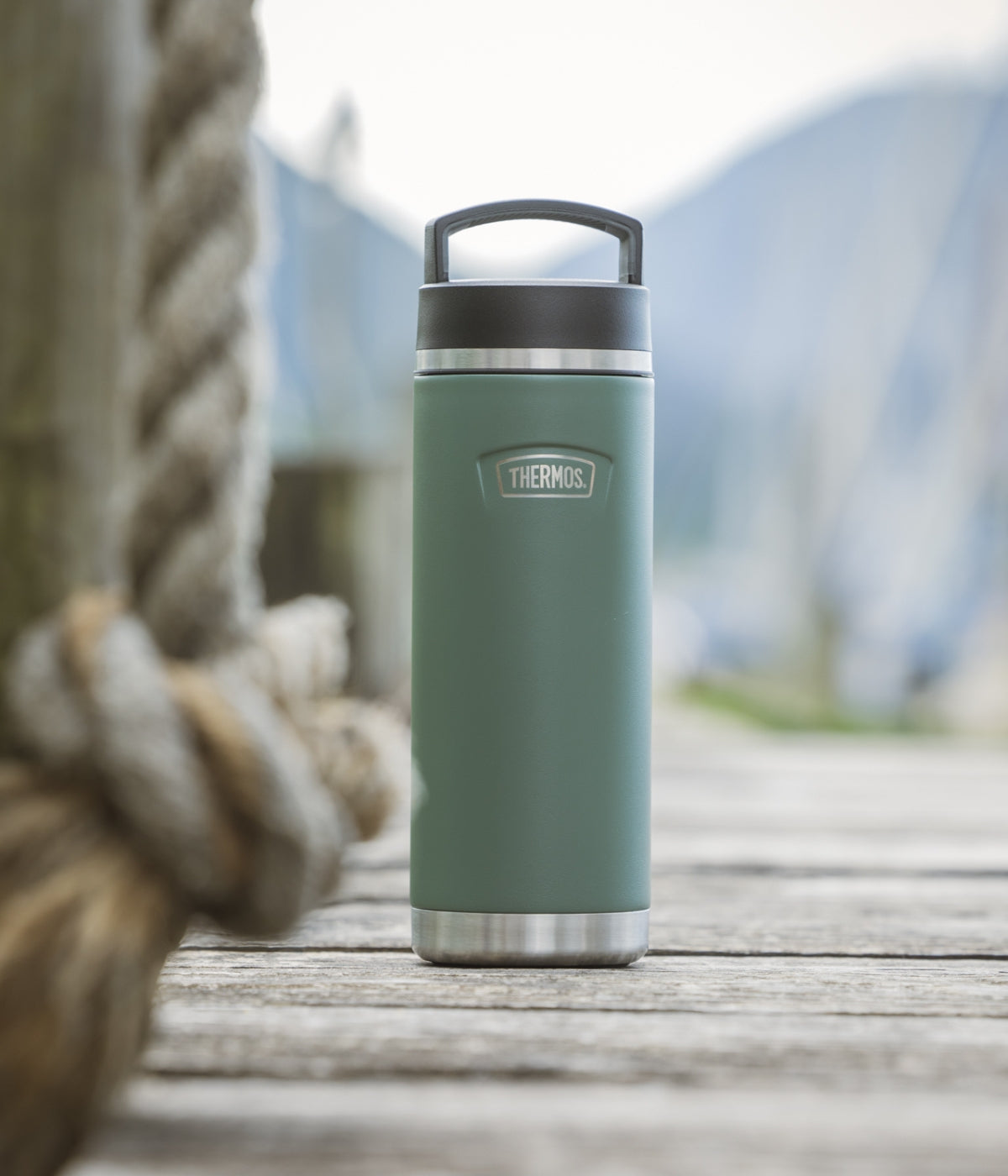 Grüne Thermoflasche auf hellem Untergrund im Outdoor-Setting